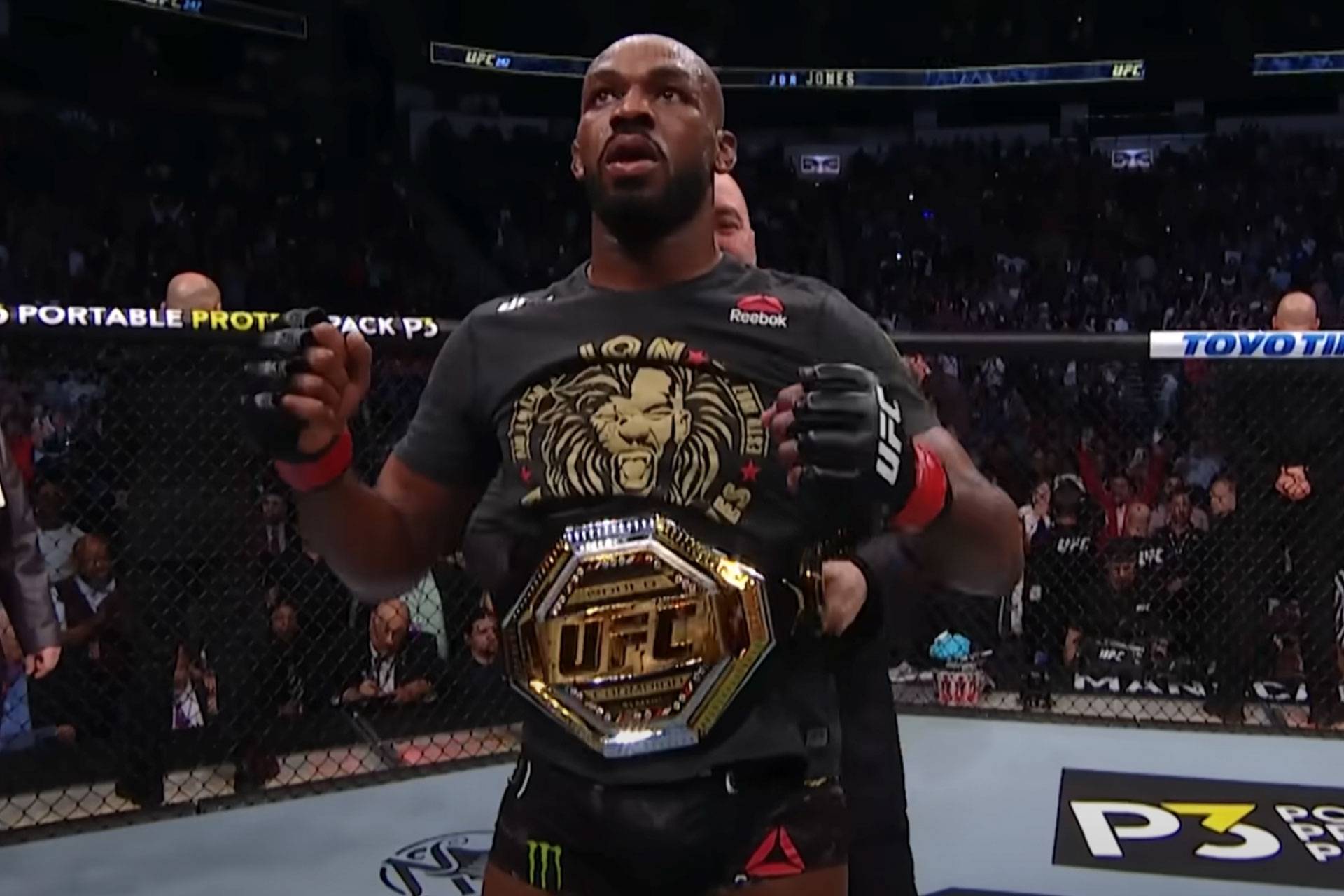 Jon Jones krijgt de UFC wereld titel omgehangen door vechtbaas Dana White.