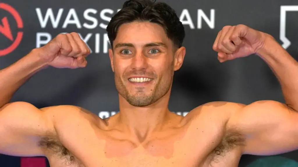 Josh Kelly flexes his muscles at a boxing weigh-in event.