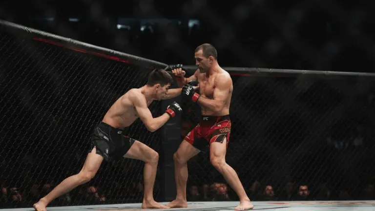 Twee MMA-vechters staan tegenover elkaar in een octagon tijdens een gespannen hoofdgevecht.