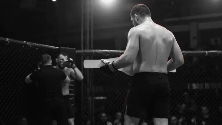 Anonieme MMA-zwaargewichtvechter met kampioensgordel in een gespannen kooi-scène